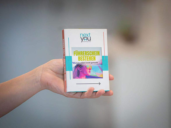 Das NextYou Kartenset „Führerschein bestehen – Dein smarter Prüfungscoach“ wird stilvoll in einer Frauenhand präsentiert. Die moderne Verpackung steht für Klarheit, Motivation und praktische Prüfungsvorbereitung. Ideal für alle, die sich gut organisiert und selbstbewusst auf die Führerschein-Theorie vorbereiten wollen.