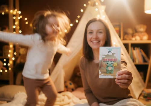 Mutter hält Mini Momente Karte während Kind im Hintergrund spielt – bewusste Familienmomente im Alltag schaffen