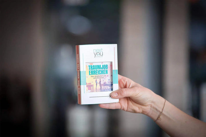 Das NextYou Kartenset „Traumjob erreichen – klar, strukturiert und selbstbewusst“ wird stilvoll in einer Hand präsentiert. Die kompakte Box steht für Klarheit, Motivation und berufliche Weiterentwicklung. Ideal für alle, die ihren Wunschjob finden, Ziele definieren und selbstbewusst ihren Karriereweg gehen möchten.